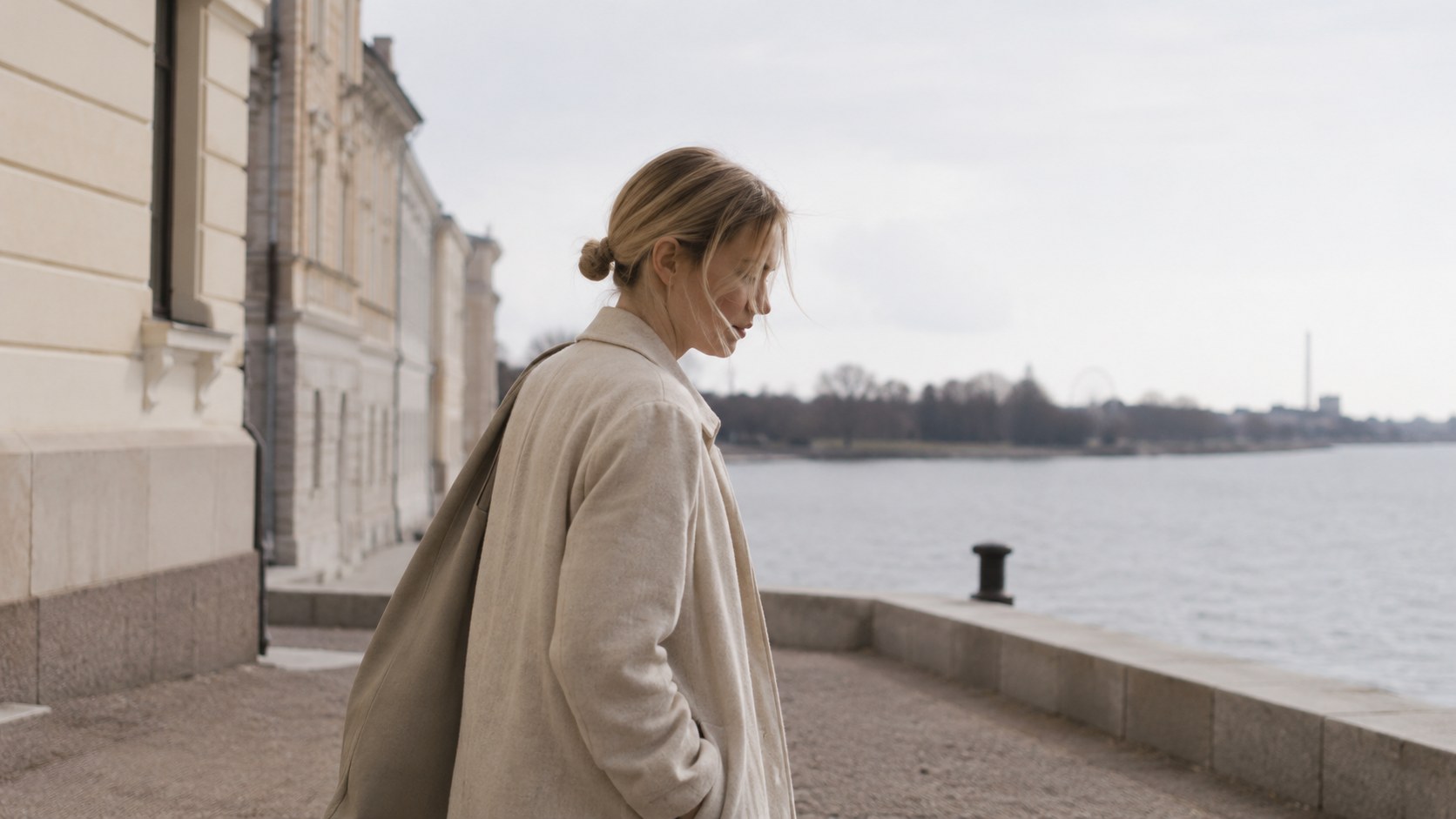 Woman walking near old Helsinki waterfront facades in pale northern light